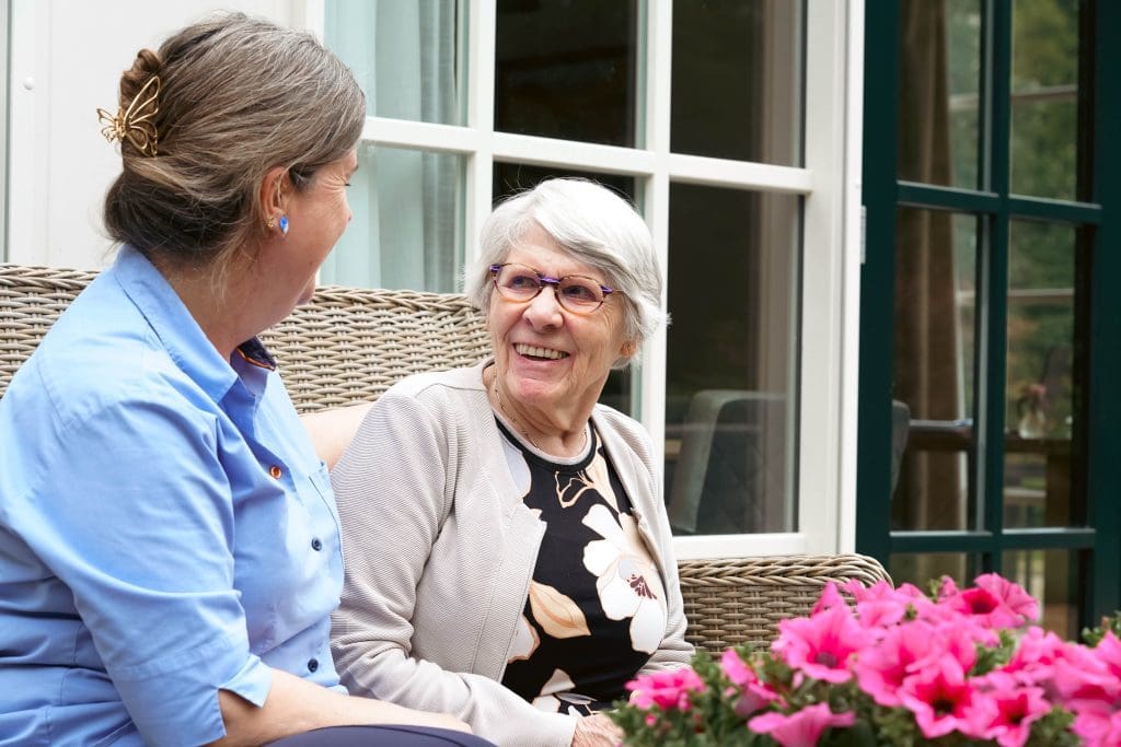 Bewoner met medewerker op bankje